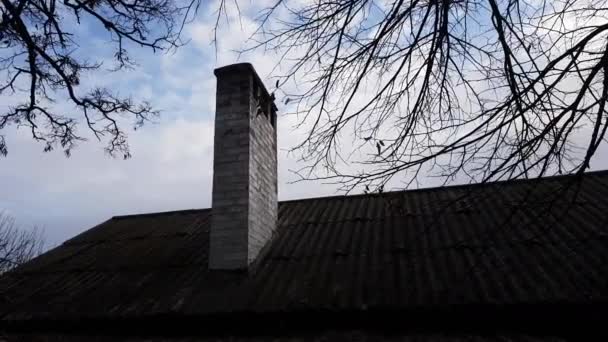 Blauer bewölkter Abendhimmel mit kahlen Ästen und einem Bauernhaus mit einer großen Kaminsilhouette — Stockvideo