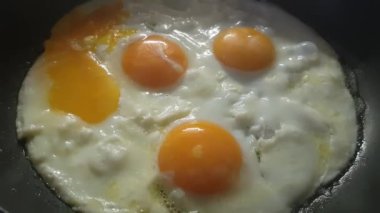 Dört tavuk yumurtası siyah bir tavada kızarır..