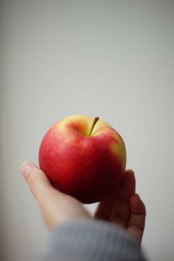 Kadın parmaklarında olgun kırmızı elma. Beyaz fırın. Yan görünüm