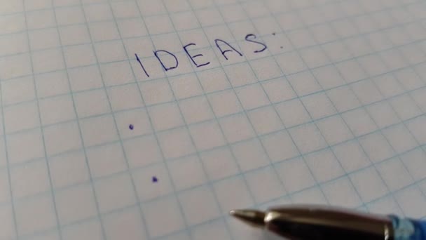 Słowa pomysły na papier w kratkę i niebieski długopis. — Wideo stockowe