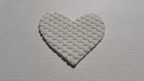 Lindo corazón blanco hecho de material texturizado latido del corazón en la mesa — Vídeos de Stock