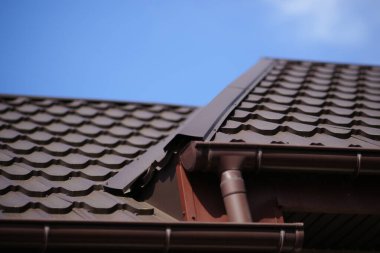 Güneşli bahar gününde kahverengi kiremitli çatının yakın çekimi.