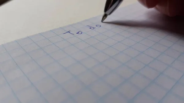 Una Mano Con Bolígrafo Azul Escribe Papel Cuadros Para Hacer —  Fotos de Stock