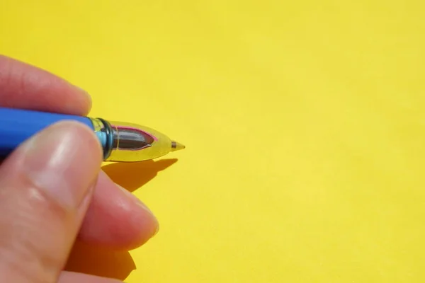 Caneta Azul Dedos Femininos Sobre Papel Amarelo Vívido — Fotografia de Stock