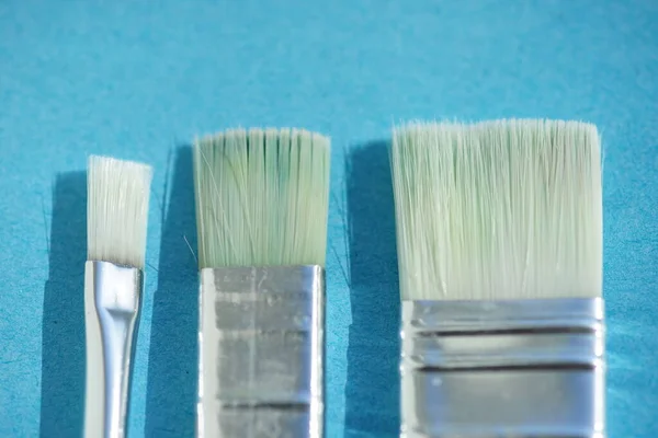 Três Pincel Plano Sintético Com Cabelo Branco Uma Mesa Azul — Fotografia de Stock