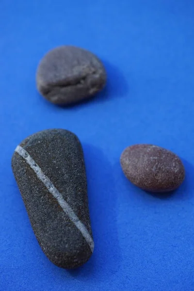 Três Pedras Seixo Cinza Escuro Mesa Azul — Fotografia de Stock