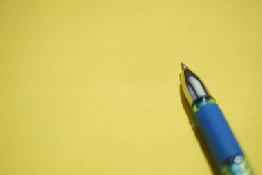 Güneşli sarı kağıtta mavi top kalem.