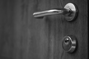 Krom saplı ve kilit delikli bir kapı. Siyah beyaz fotoğraf.