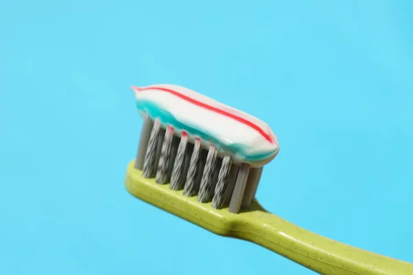 Escova Dentes Plástico Verde Com Pasta Dentes Listrada Fundo Azul — Fotografia de Stock