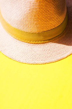 Güneşli sarı masada açık pembe kadın şapkası.