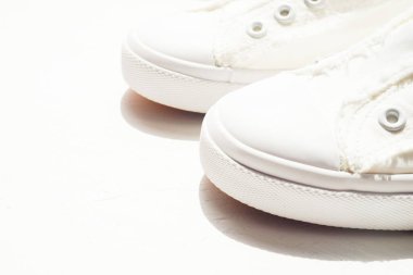 Güneşli taş zeminde yeni beyaz spor ayakkabılar