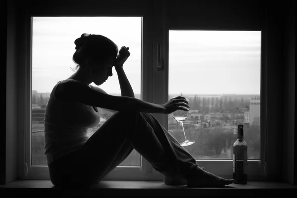 Woman in depressed mood sits on the window — Stock Photo, Image