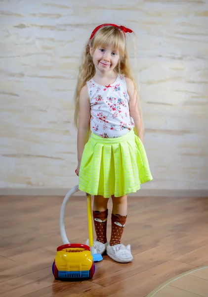 Schattig klein blond meisje stofzuigen het huis — Stockfoto