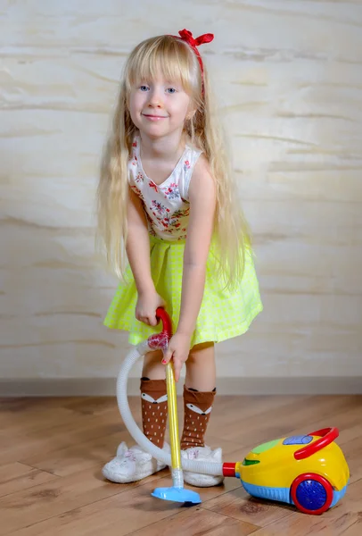 Schattig klein blond meisje stofzuigen het huis — Stockfoto