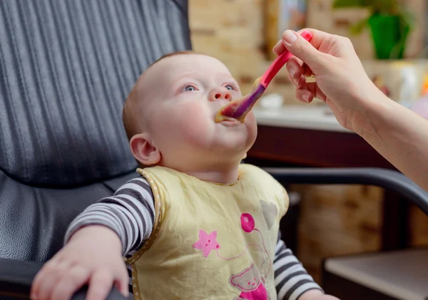 Baby met voedsel rond zijn mond zitten op stoel — Stockfoto