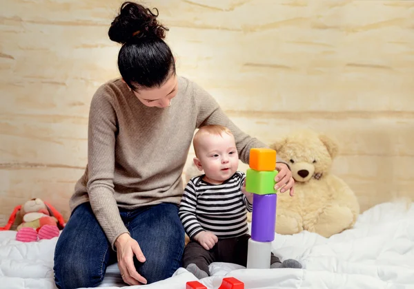 Mamma e il suo bambino carino giocare con blocchi di plastica — Foto Stock