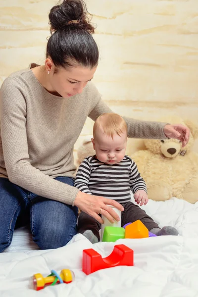 Mamá dando juguetes plásticos a su bebé llorón —  Fotos de Stock