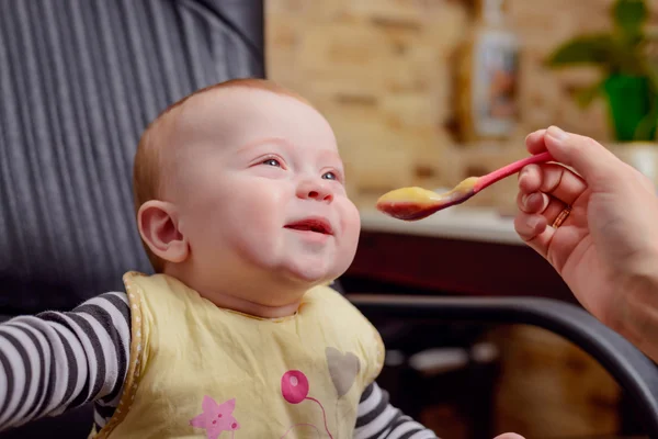 Bebé feliz en silla comiendo comida de gachas —  Fotos de Stock