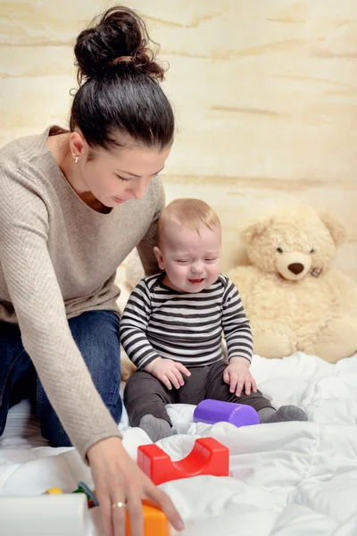 Mamá dando juguetes plásticos a su bebé llorón — Foto de Stock