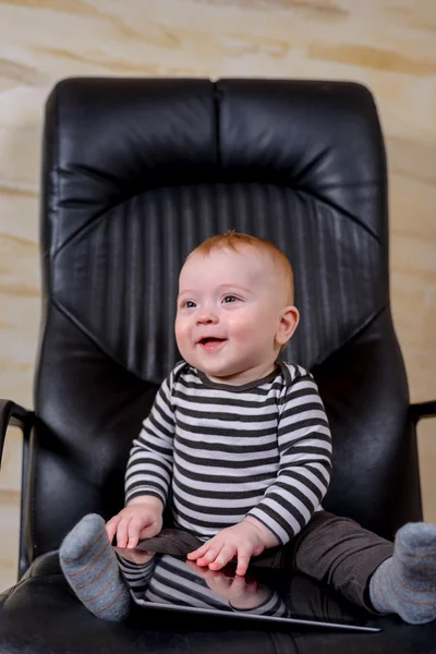 Niño lindo con la tableta sentada en la silla de oficina — Foto de Stock