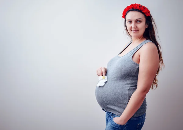 Gravid kvinna i blå jeans hålla tossor — Stockfoto