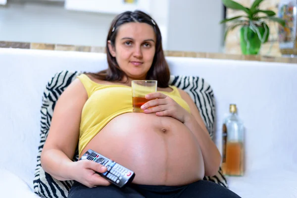 妊娠中の女性と酒とリモート コントロール — ストック写真