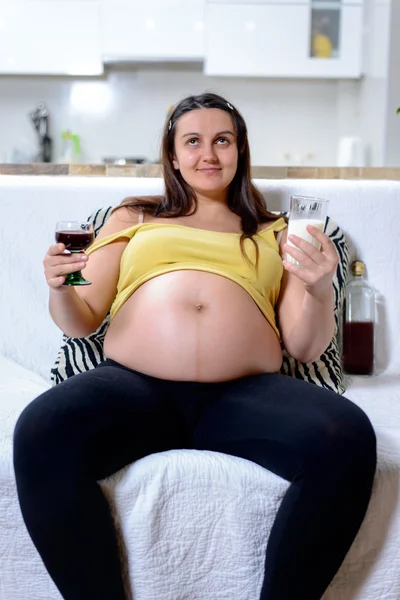 Kobieta w ciąży trzyma wino i mleka — Zdjęcie stockowe