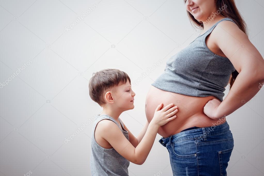 Little boy kissing belly of pregnant mom