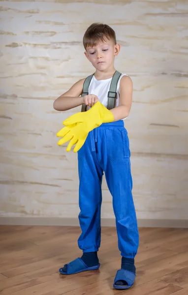 Serious boy in slippers putting on gloves — Stock Photo, Image