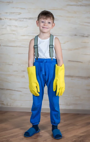 Serious boy in slippers putting on gloves — Stock Photo, Image