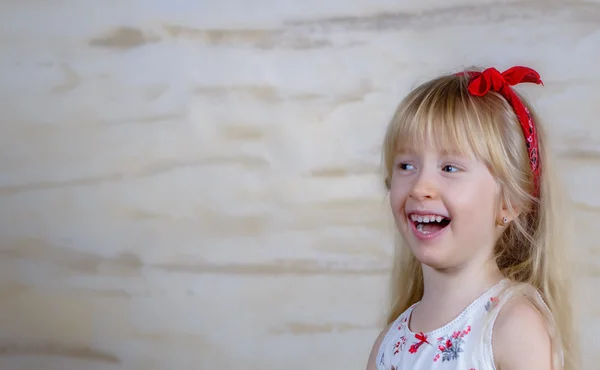 Lachen kleines blondes Mädchen mit roter Schleife — Stockfoto