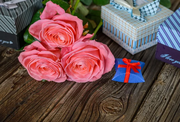 Bundle of roses and gifts on table — Stock Photo, Image
