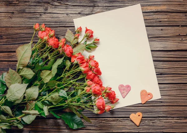 Чистый лист бумаги на деревянной поверхности с розами — стоковое фото