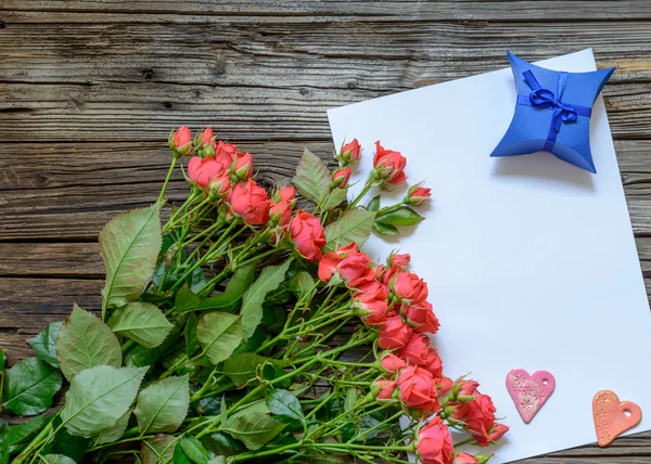 Folha de papel em branco na superfície de madeira com rosas — Fotografia de Stock