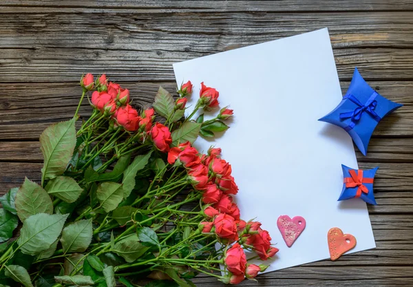 Tomma pappersark på träytan med rosor — Stockfoto