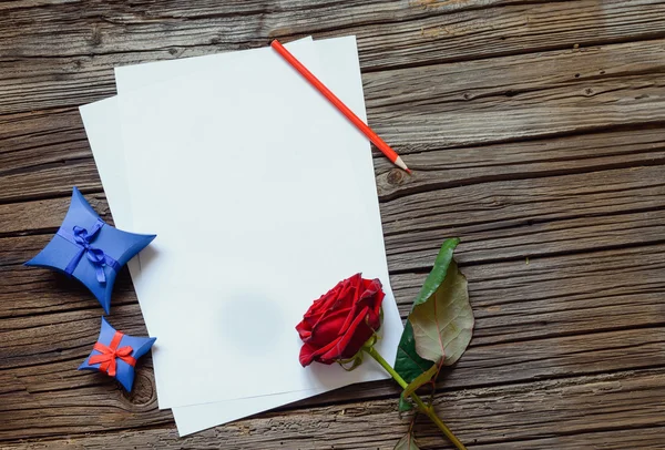 Papeles en blanco sobre mesa con rosa y regalo —  Fotos de Stock