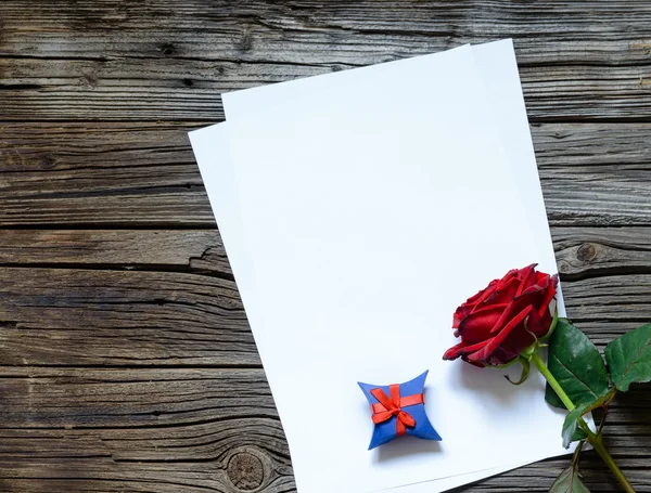 Papeles sobre mesa con rosa roja y regalo —  Fotos de Stock