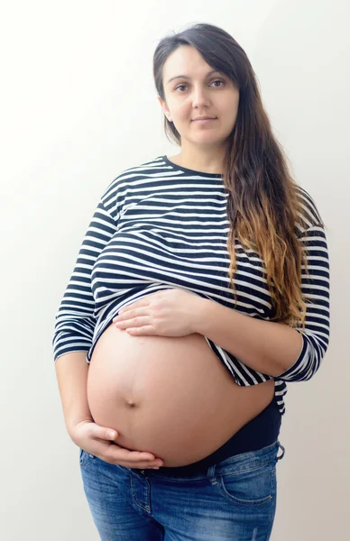 Těhotná žena v dlouhých vlasech drží břicho — Stock fotografie