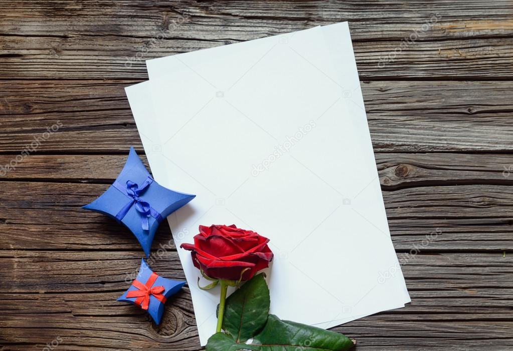 Papers on table with red rose and gift