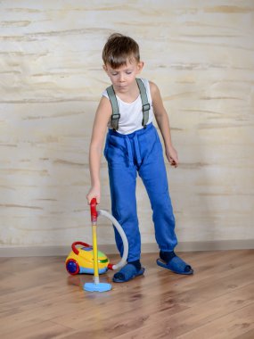 Cute boy using toy vaccuum
