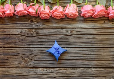 Güller ile ahşap arka plan üzerinde Tiny hediye kutusu