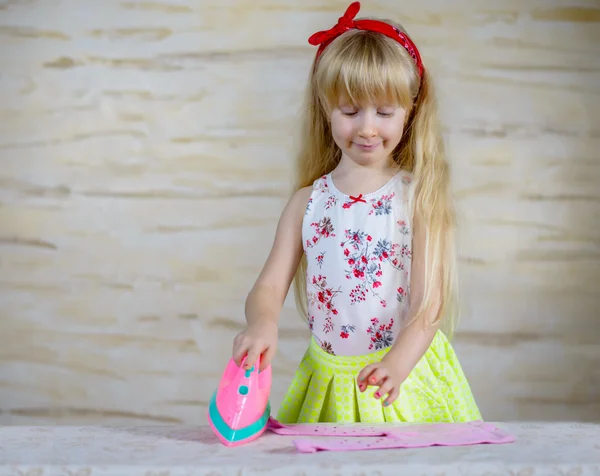 Cheerful little girl using toy iron — Stock Photo, Image