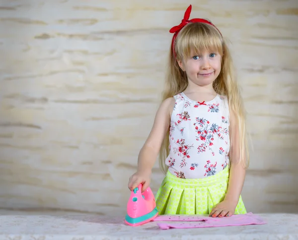 Cheerful little girl using toy iron — Stock Photo, Image