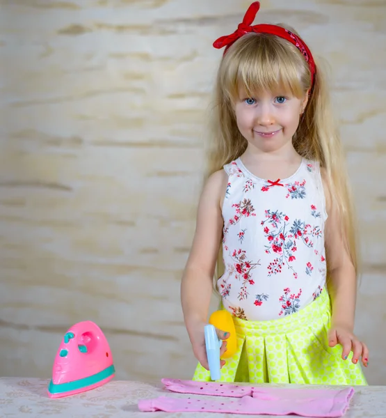 Cheerful little girl using toy iron — Stock Photo, Image