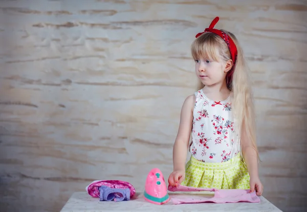 Cheerful little girl using toy iron — Stock Photo, Image