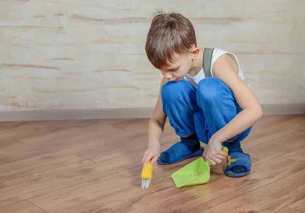 Child using toy broom and dustpan — Stok fotoğraf