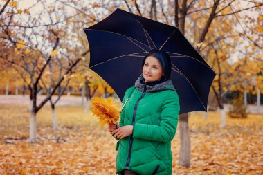 Yaprakları ve şemsiyetutan sevimli genç kadın