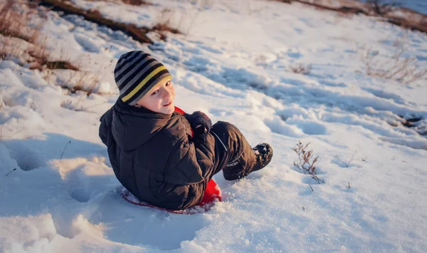 Malé dítě sáňkování po zasněženém svahu — Stock fotografie