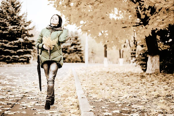 Mulher solteira andando na calçada com folhas — Fotografia de Stock
