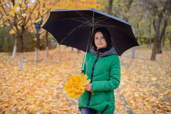 Schöne junge Frau in grünem Mantel mit Blättern — Stockfoto